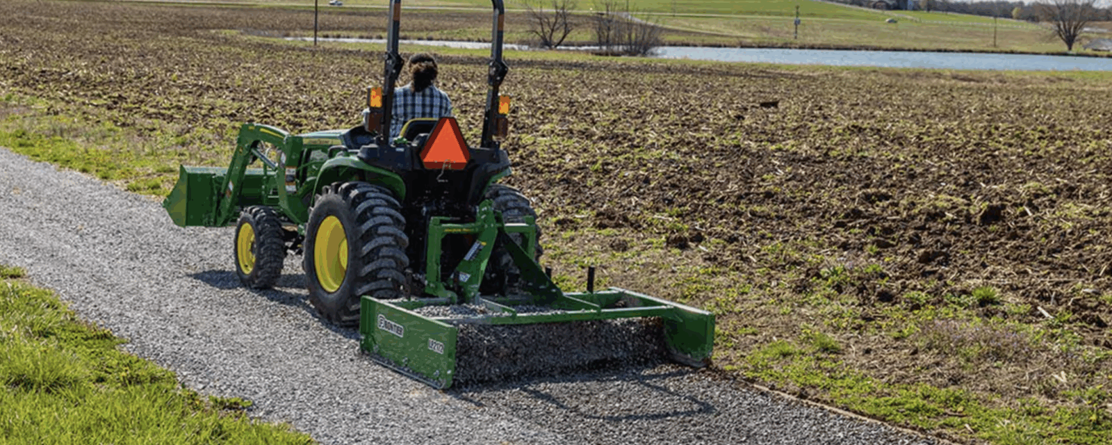 A John Deere three-point box blade on a driveway